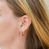 close up of blond woman's ear wearing a small gold hoop earrings